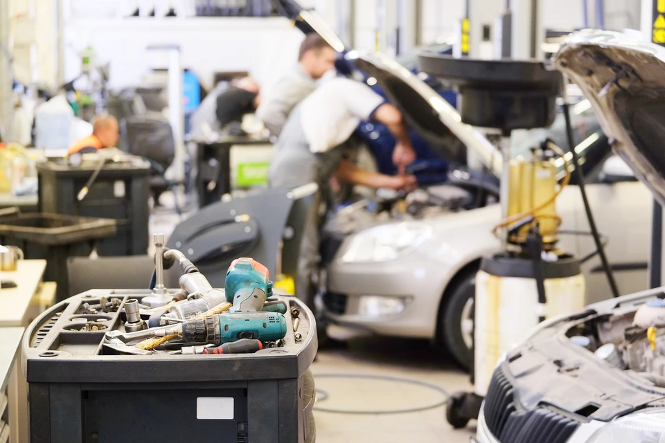 Atelier automobile avec mécaniciens en blouses blanches travaillant sur véhicules, capots ouverts