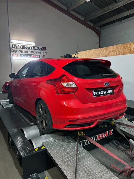 Atelier automobile intérieur avec Ford Focus rouge sur banc d'essai dynamométrique
