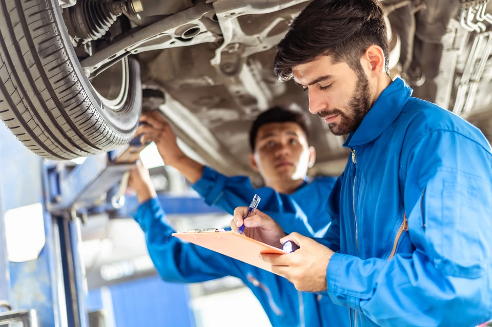 Un homme en tenue professionnelle examine attentivement l'intérieur d'un véhicule dans un environnement de concession automobile