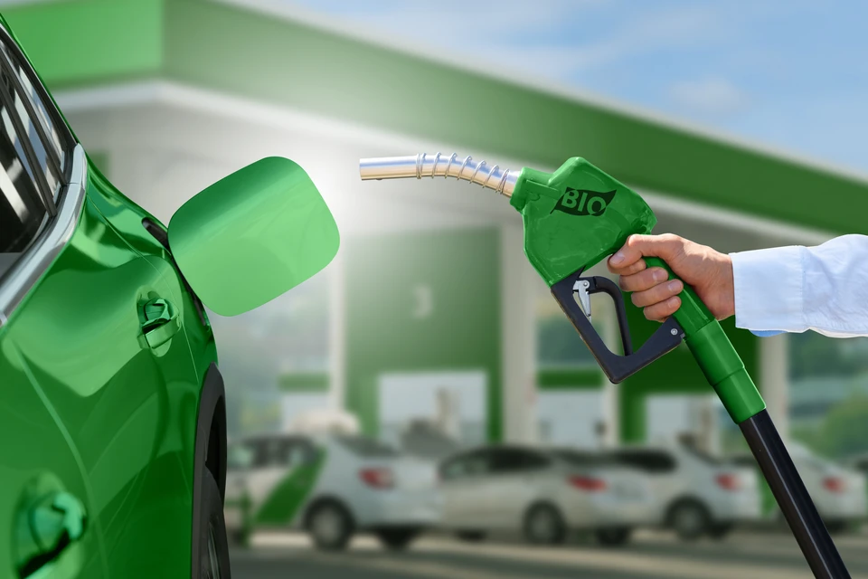 Mécanicien automobile en combinaison bleue effectuant un réglage de géométrie sur roue avant d'un véhicule dans un garage professionnel