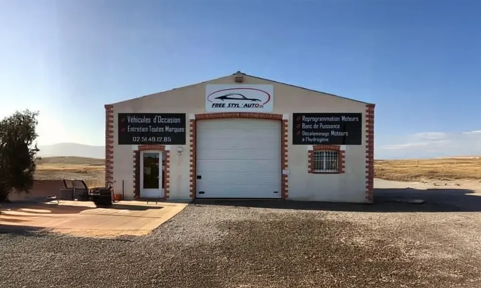 Mécanicien automobile en combinaison de travail bleue tenant des clés dans un garage professionnel